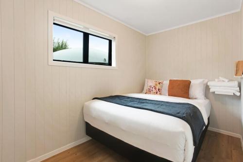 a small bedroom with a bed and a window at Countryside 4BR Family Home near Airport in Auckland