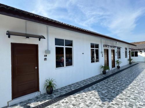 a white building with a brown door and windows at D' Ehsan Homestay & Chalet in Kuala Terengganu