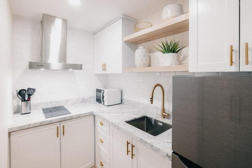 a white kitchen with a sink and a microwave at Modern Coastal Design 1 BR Condo Golf View BGC in Manila