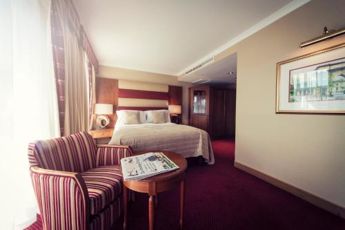 a hotel room with a bed and a chair and a table at Carlton George Hotel in Glasgow