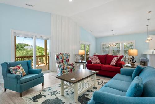 a living room with two blue chairs and a red couch at Tranquility Cove in Nags Head