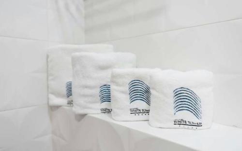 a row of white towels sitting on a shelf at White Tower Apart Hotel in Mamaia