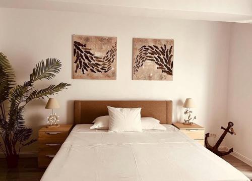 a bedroom with a bed with three paintings on the wall at White Tower Apart Hotel in Mamaia