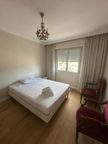- une chambre avec un lit, une chaise et un lustre dans l'établissement Vue mer panoramique pour ce 3 pièces a 7 minutes a pied du palais du festival, à Cannes