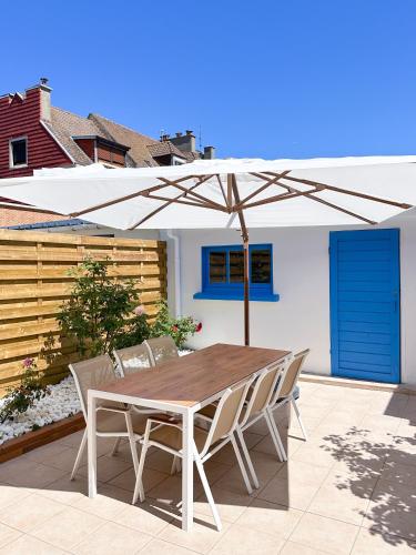 a wooden table and chairs under an umbrella on a patio at L'Heurt Bleue - Maison de pêcheur face mer in Le Portel