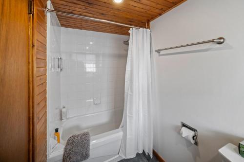a bathroom with a shower with a white shower curtain at Mountain View Retreat in the heart of Banff - Massive House Sleeps 23 in Banff