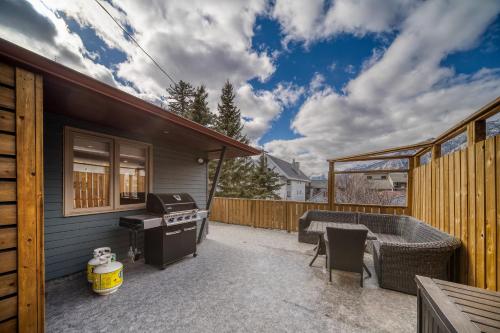 a patio with a grill and a barbecue on a house at Mountain View Retreat in the heart of Banff - Massive House Sleeps 23 in Banff