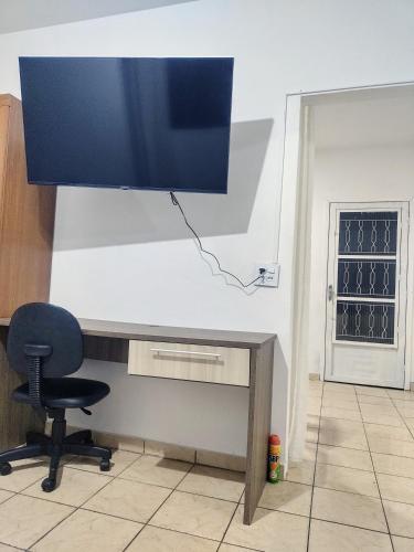 a desk with a chair and a monitor on a wall at Ap SOL in Piracicaba