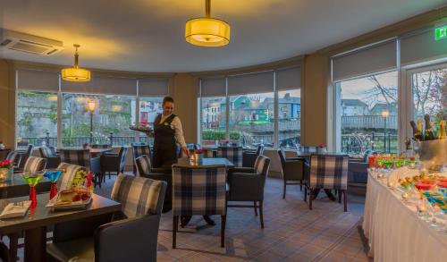 a woman standing in a restaurant with tables and chairs at Kilkenny River Court Hotel in Kilkenny