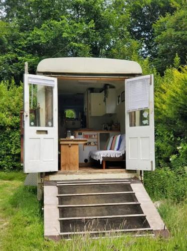 a small house with a door and a table at Monroe Horsebox Glamping in Porthleven