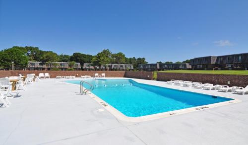 a large swimming pool with white lounge chairs and chairs at Villas M1 in Nags Head