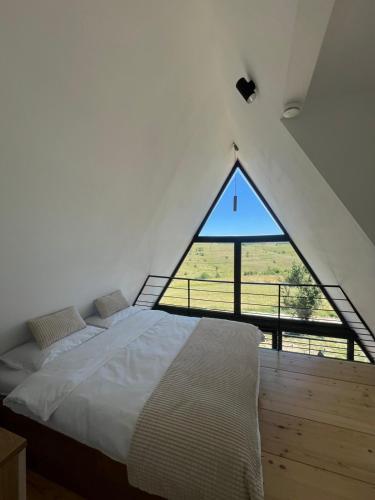 a bed in a room with a large window at TriPeak in Bjelašnica