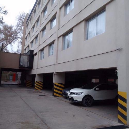a white car is parked in a garage next to a building at Gran Hotel Dakar in Mendoza