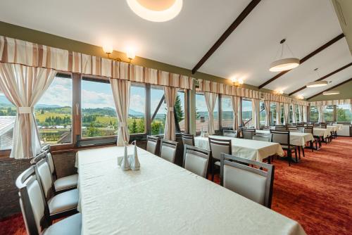 a dining room with tables and chairs and windows at Pensiunea La Bella Vista in Poiana Negrii
