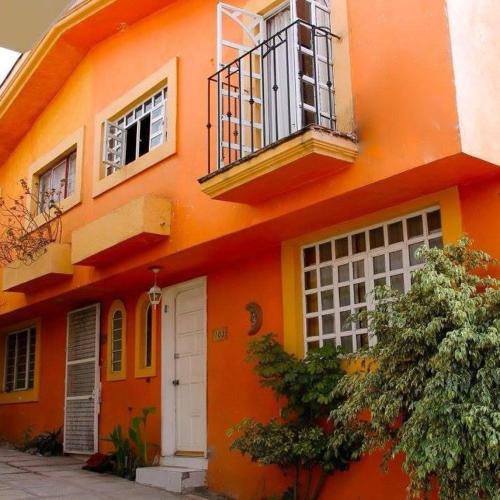 an orange building with a balcony and a door at BUAP CU Casa Nopal in Chapulco