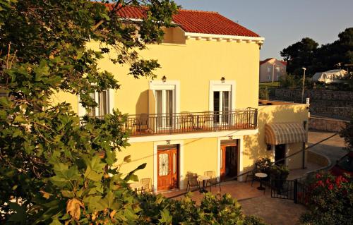 żółty dom z balkonem przed nim w obiekcie Bacan Serviced Apartments w mieście Cavtat