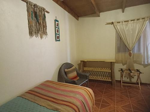a bedroom with a bed and a chair and a window at Casa Ñujtas - cultura, viajes, experiencias in San Pedro de Atacama