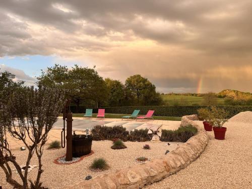 un jardin avec des chaises et un arc-en-ciel en arrière-plan dans l'établissement Maison M, à Surin