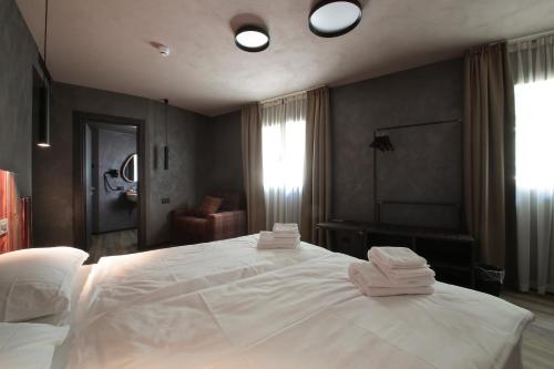 a bedroom with a large white bed with towels on it at Crimea Wine Hotel in Chiavenna