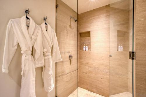 a bathroom with a shower and a white coat hanging on a wall at For couples, petfriendly 2 BR ocean view 18 4pax in Cabo San Lucas