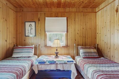 two beds in a room with wooden walls at Y Go By in Kennebunkport