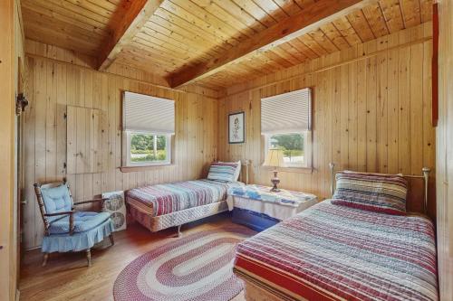 a bedroom with two beds and a chair in a cabin at Y Go By in Kennebunkport
