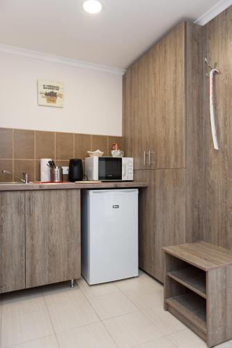 a kitchen with wooden cabinets and a white refrigerator at Dorottya Vendégház in Hódmezővásárhely