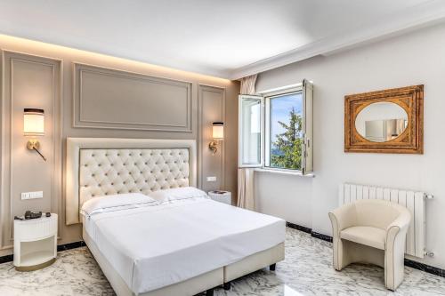 a bedroom with a white bed and a chair at Hotel Castel Vecchio in Castel Gandolfo