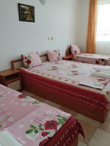 two beds in a room with flowers on them at Sani Family Hotel in Byala