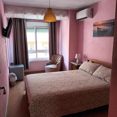 a bedroom with a bed and a chair and a window at Habitación en centro de Alicante in Alicante