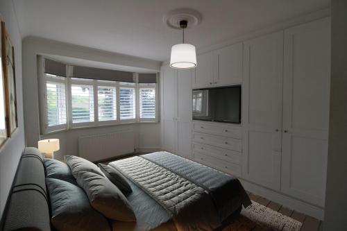 een woonkamer met een bank en een televisie bij Stunning Caterham 4 bedroom home in Kenley