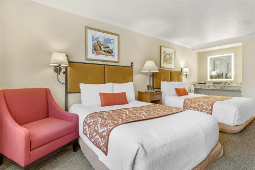 a hotel room with two beds and a red chair at Best Western Plus Arroyo Roble Hotel & Creekside Villas in Sedona