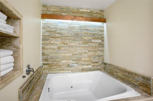 a white tub in a bathroom with a brick wall at Best Western Plus Arroyo Roble Hotel & Creekside Villas in Sedona