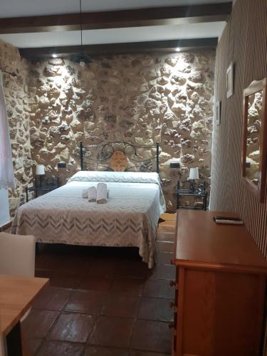 a bedroom with a bed and a stone wall at Casa Rural Los Parrales in El Tranco