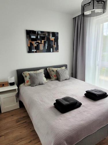 a bedroom with a bed with two black pillows on it at Jantar Resort Apartament in Jantar