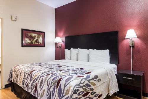 a large bed in a hotel room with red walls at Red Roof Inn Atlanta - Kennesaw State University in Kennesaw