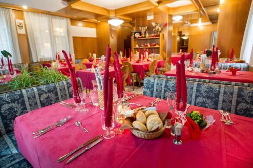 a table with a red table cloth with a basket of food at Albergo Italia in Molveno