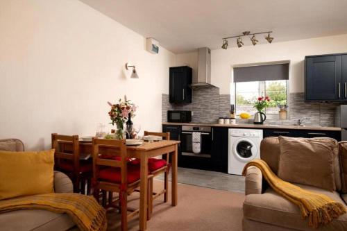 a living room with a table and a kitchen at Martinmas Cottage in Flamborough