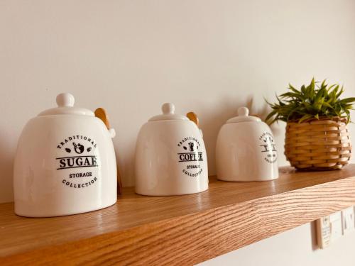 four white milk containers sitting on a wooden shelf at Dream Apartment - Near Beach with Pool View & WiFi in Salalah