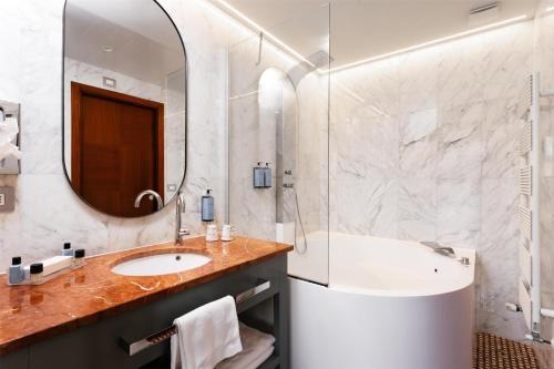 a bathroom with a sink and a tub and a mirror at Best Western Hotel Nazionale in Sanremo
