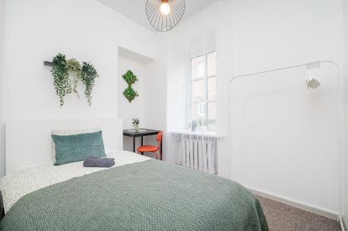 a white bedroom with a bed and a window at City Nest Vilnius Oldtown in Vilnius