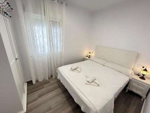 ein weißes Schlafzimmer mit einem weißen Bett und einem Fenster in der Unterkunft Apartamento Empul Barrosa Beach in Novo Sancti Petri