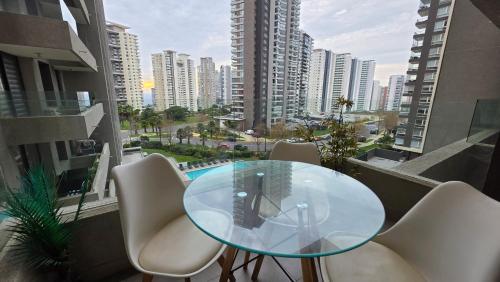 a glass table and chairs on a balcony with a city at Oceana Suites Eco Costas in Concón