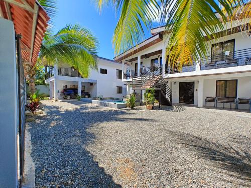 a house with palm trees and a gravel driveway at AJ House & Suites in Uvita