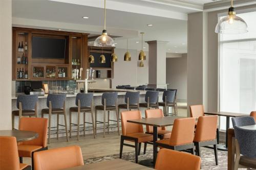 a restaurant with tables and chairs and a bar at Hilton Garden Inn Riverhead in Riverhead