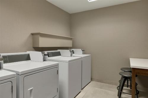a laundry room with white appliances and a table and stool at Hilton Garden Inn Riverhead in Riverhead