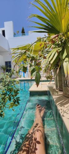 a person laying in a swimming pool at Dar R'Bat, Maison d'Hôtes de charme in Nabeul