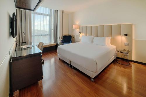 a bedroom with a large white bed and a window at NH Napoli Panorama in Naples