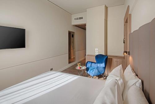 a bedroom with a bed and a tv and a blue chair at NH Napoli Panorama in Naples