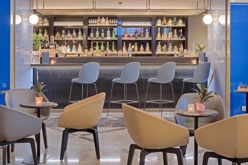 a bar with chairs and a counter with bottles at NH Napoli Panorama in Naples